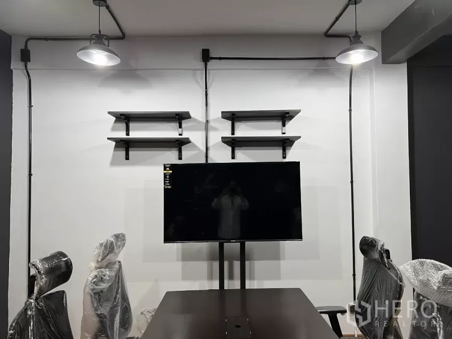 带办公室的家 出租在Pom Prap Sattru Phai, Bangkok - 会议区墙面设置置物架与挂装电视，外露管线与吊灯。
