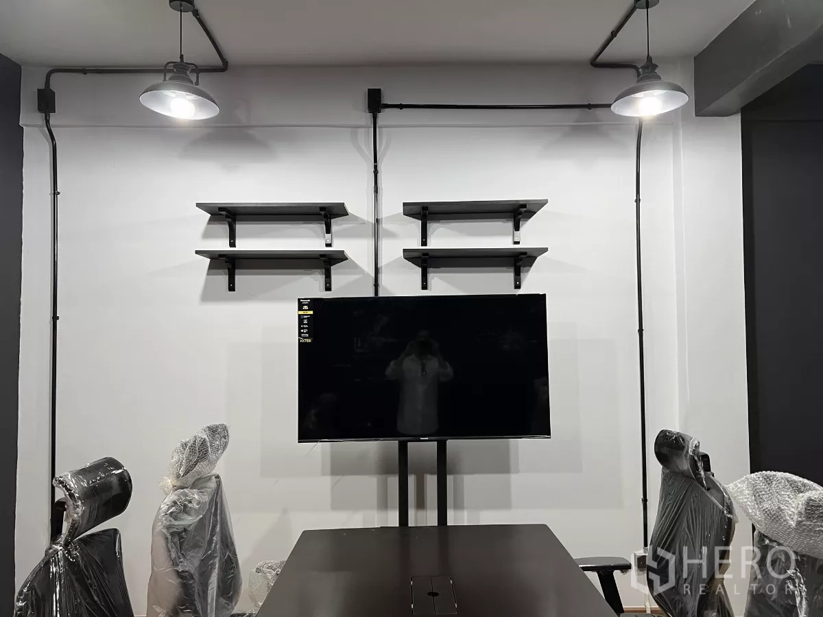 带办公室的家 出租在Pom Prap Sattru Phai, Bangkok - 会议区墙面设置置物架与挂装电视，外露管线与吊灯。