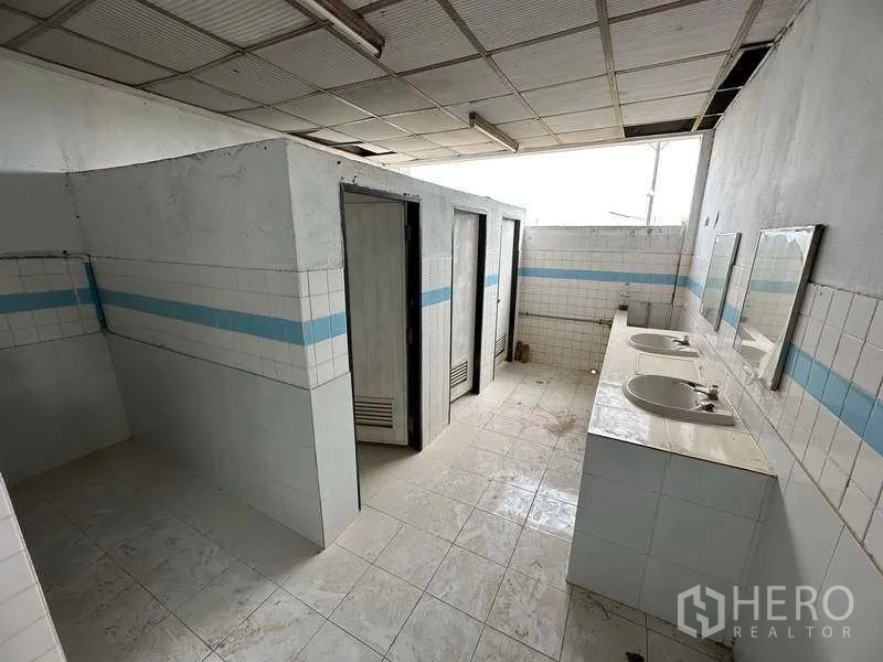Factory for rent in Sai Noi, Nonthaburi - Staff restroom with tiled walls, separate stalls and double sink counter.