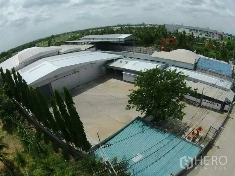 Warehouse for rent in Pak Kret, Nonthaburi - Aerial view of a large logistics warehouse compound with a wide concrete yard and metal roofs in Pak Kret, Nonthaburi.