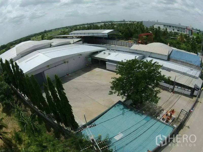 Warehouse for rent in Pak Kret, Nonthaburi - Aerial view of a large logistics warehouse compound with a wide concrete yard and metal roofs in Pak Kret, Nonthaburi.