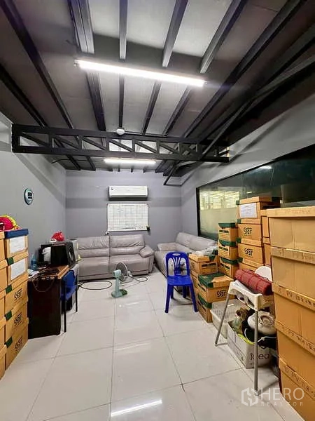 Warehouse for rent in Prawet, Bangkok - Air-conditioned small office filled with boxes and sofas for storage.