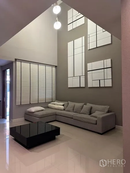 联排别墅 出售在Saphan Sung, Bangkok - 挑高客厅，L 型沙发、特色墙与吊灯点缀。