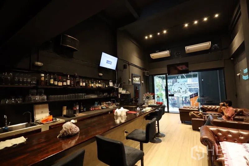 店屋 出租或出售在Watthana, Bangkok - 长木质吧台，高脚椅与酒具架，临街玻璃入口