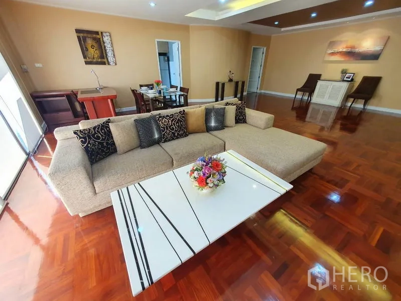 公寓 出租在Watthana, Bangkok - 宽敞客厅，转角沙发、白色茶几与抛光木地板