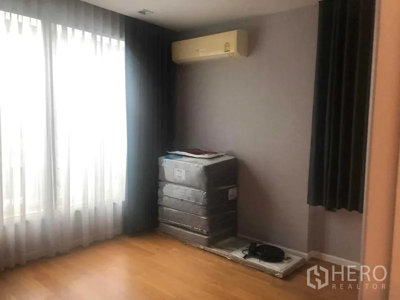 Detached House for rent or sale in Bang Kapi, Bangkok - Bright spare bedroom with wood flooring, large window and split air conditioner.