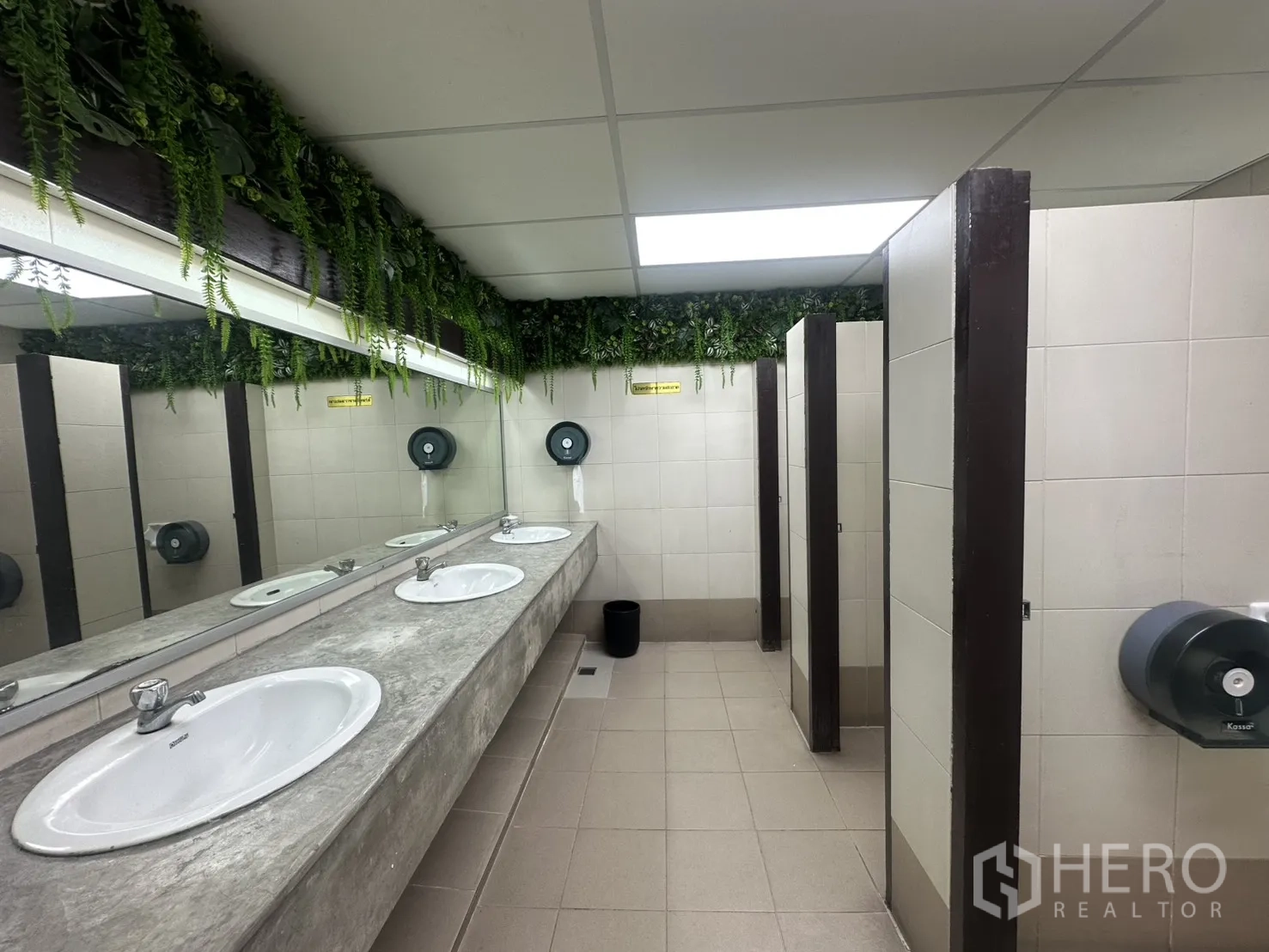 Office Space for rent in Bang Rak, Bangkok - Restroom with multiple sinks, large mirror, and toilet stalls with greenery accents.