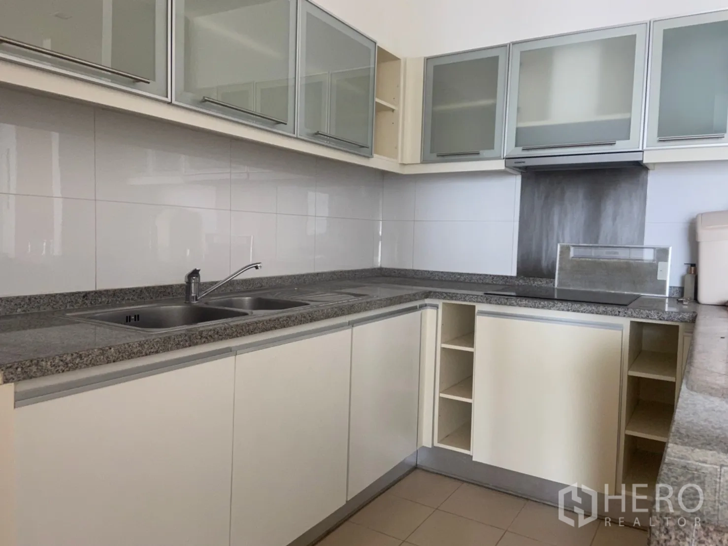 Condominium for rent or sale in Khlong Toei, Bangkok - U-shaped kitchen with granite countertops, double sink, glass-front cabinets and built-in hood.