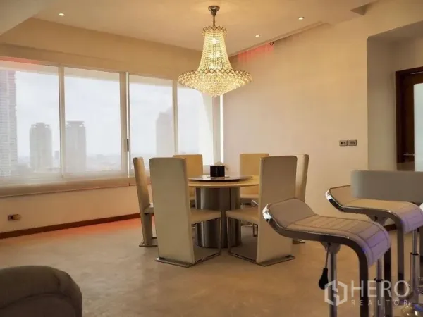 Condominium for rent in Khlong San, Bangkok - Bright dining area with crystal chandelier and breakfast bar beside large windows.