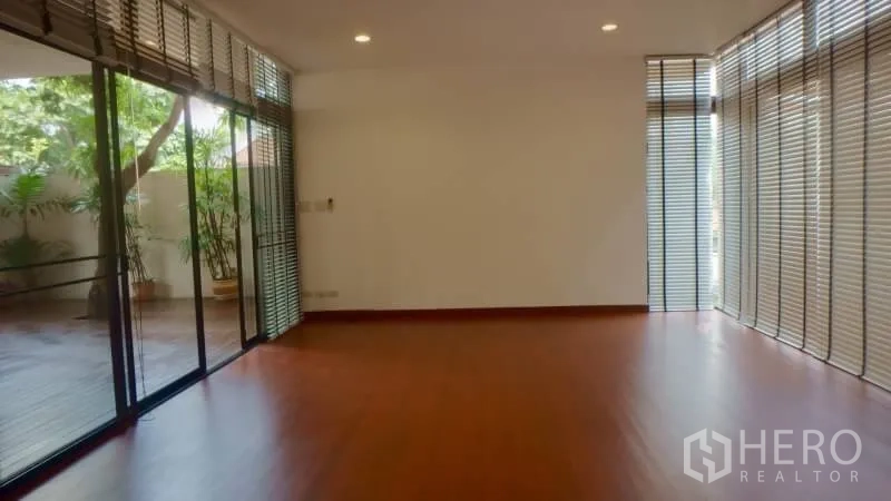 Detached House for rent in Watthana, Bangkok - Open-plan room with sliding glass doors to a decked patio and vertical blinds.