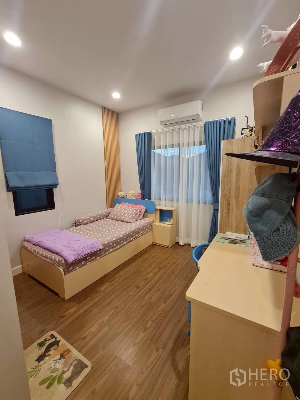 Detached House for rent or sale in Lam Luk Ka, Pathum Thani - Cozy secondary bedroom with a single bed, study desk and blue curtains.