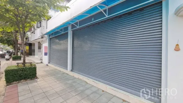 店屋 出租 - 带蓝色雨棚与双卷闸的店铺外立面与人行道