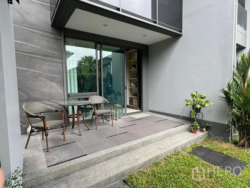 Detached House for rent in Bang Kapi, Bangkok - Covered patio with outdoor table and chairs by sliding glass doors overlooking the lawn.