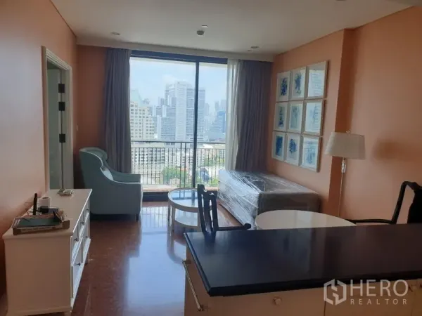 Condominium for rent in Khlong Toei, Bangkok - Bright living area with floor-to-ceiling window, balcony and wide Bangkok skyline view.