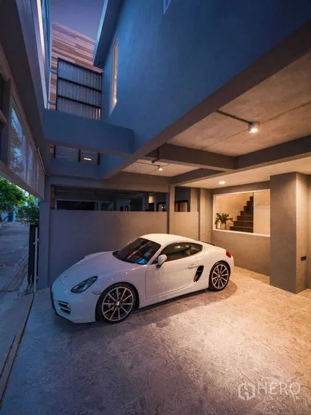 Townhouse for rent in Watthana, Bangkok - Covered carport at townhouse entrance with ceiling lights and white sports car.