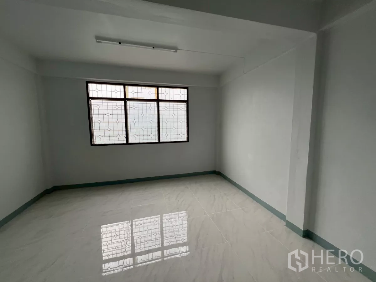 Shophouse for rent in Khlong Toei, Bangkok - Sunlit room featuring polished white tiles and a large grilled window.