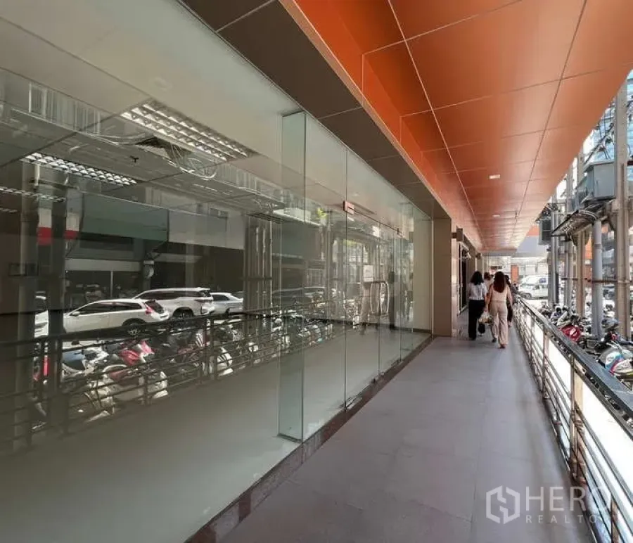 Retail Space for rent in Pathum Wan, Bangkok - Glass-front retail shop along a covered walkway with orange ceiling panels in central Bangkok.