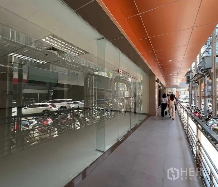 Retail Space for rent in Pathum Wan, Bangkok - Glass-front retail shop along a covered walkway with orange ceiling panels in central Bangkok.