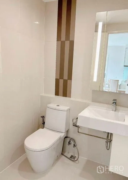 公寓 出租在Watthana, Bangkok - 整洁的客卫，马桶、壁挂式洗手台与竖向装饰砖。