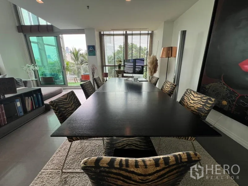 Condominium for sale in Khlong San, Bangkok - Long dining table with zebra-print chairs by the windows and greenery views.