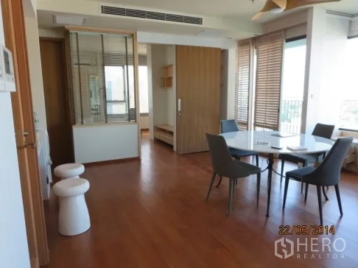 Condominium for rent in Bang Rak, Bangkok - Dining area with a round table and four chairs on wood flooring beside windows.