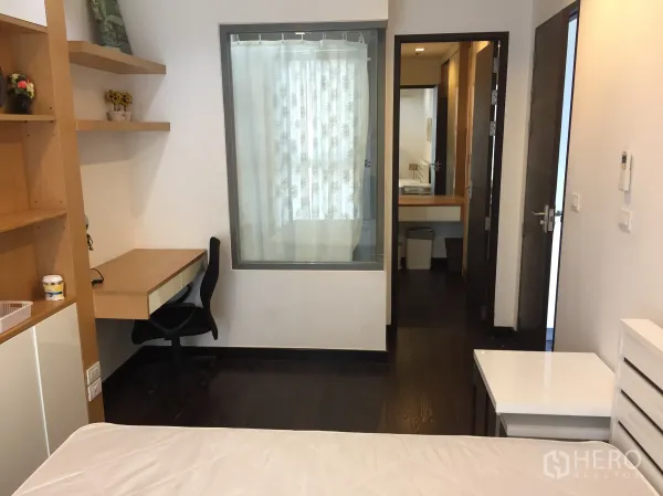 公寓 出租在Ratchathewi, Bangkok - 卧室带内置书桌与置物架，玻璃隔断与深色木地板。
