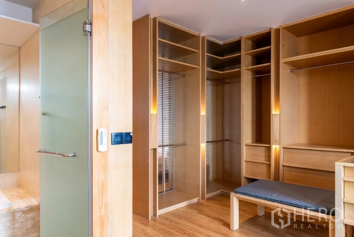 Townhouse for rent in Lat Phrao, Bangkok - Walk-in dressing room with illuminated wooden cabinetry and bench.