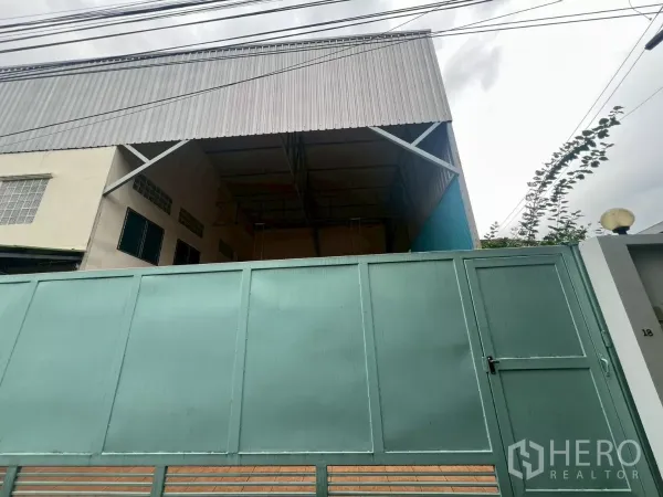 Warehouse for rent in Lat Phrao, Bangkok - Street-facing warehouse exterior with tall metal gate and covered loading bay.