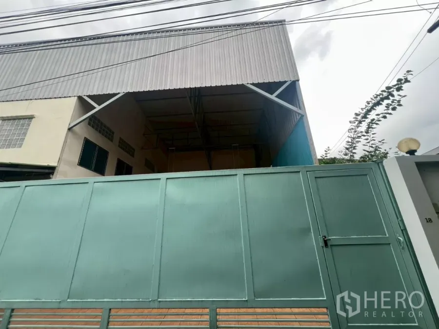 Warehouse for rent in Lat Phrao, Bangkok - Street-facing warehouse exterior with tall metal gate and covered loading bay.