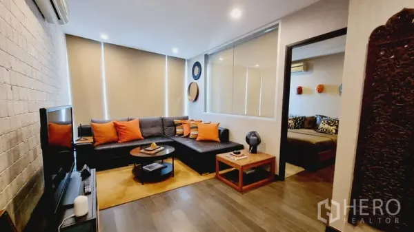 คอนโด ขายในWatthana, Bangkok - ห้องนั่งเล่นโซฟาหนังทรง L ชั้นวางทีวี และแสงไฟอบอุ่น