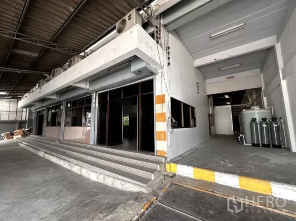 Factory for rent in Bang Phli, Samut Prakan - Close view of office entrance beside a ramped loading dock with safety-striped columns.