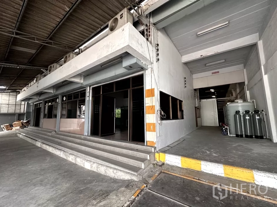 Factory for rent in Bang Phli, Samut Prakan - Close view of office entrance beside a ramped loading dock with safety-striped columns.