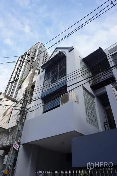 Home Office for rent in Khlong Toei, Bangkok - Street view of a multi-storey building facade with balcony and glass blocks.
