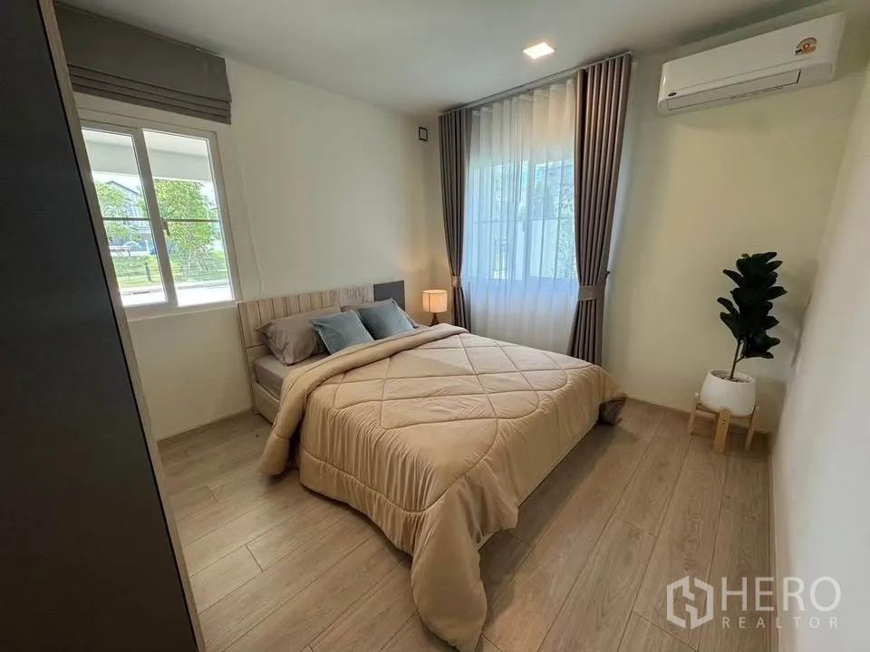 Detached House for rent in Bang Phli, Samut Prakan - Cozy bedroom with a double bed, curtains, and wood-look flooring.