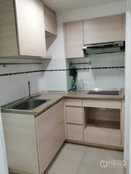 公寓 出售在Yan Nawa, Bangkok - 紧凑L形厨房，浅木橱柜、水槽、炉灶与抽油烟机。