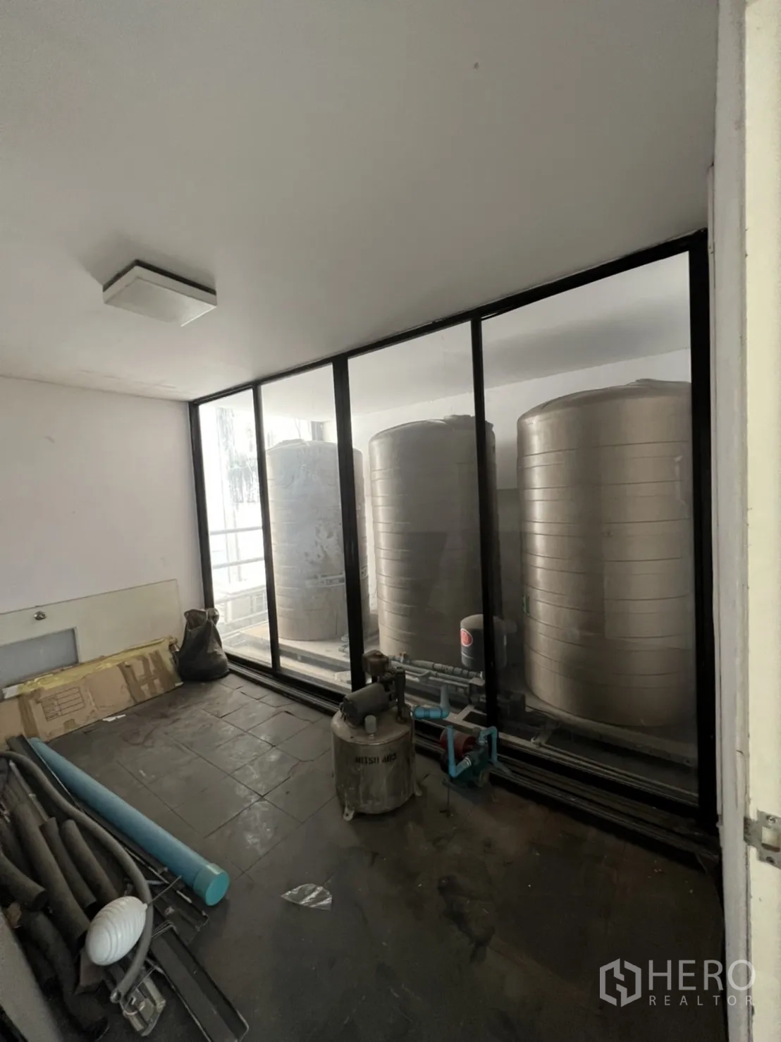 Shophouse for rent or sale in Watthana, Bangkok - Utility room with large water tanks behind a glass partition.