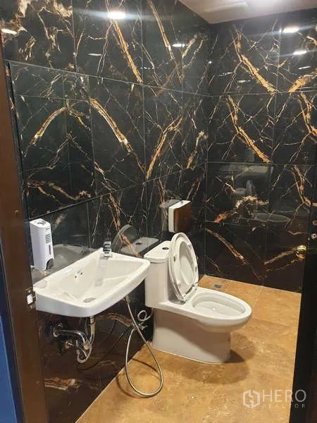 Home Office for rent in Khlong Toei, Bangkok - Contemporary restroom with black marble walls and white fixtures.