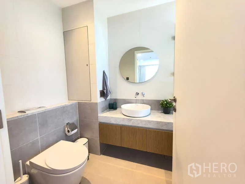 Apartment for rent - Bright bathroom at Holme Ekkamai 22 with round mirror, vessel sink and wall-hung toilet.