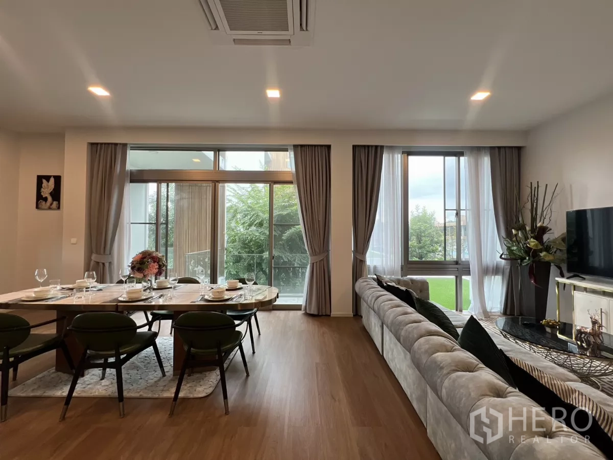 Detached House for rent in Saphan Sung, Bangkok - Cozy living room with sectional sofa and dining table under recessed lights.