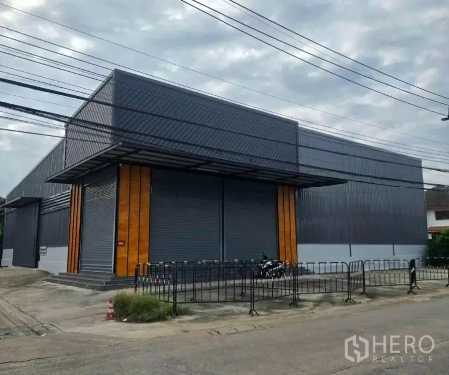 Warehouse for rent in Khlong Toei, Bangkok - Modern steel-clad warehouse exterior with twin roller shutters and covered loading area on a corner lot.