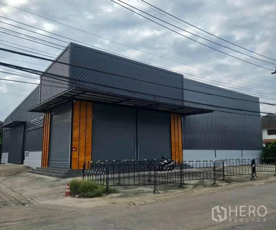 Warehouse for rent in Khlong Toei, Bangkok - Modern steel-clad warehouse exterior with twin roller shutters and covered loading area on a corner lot.
