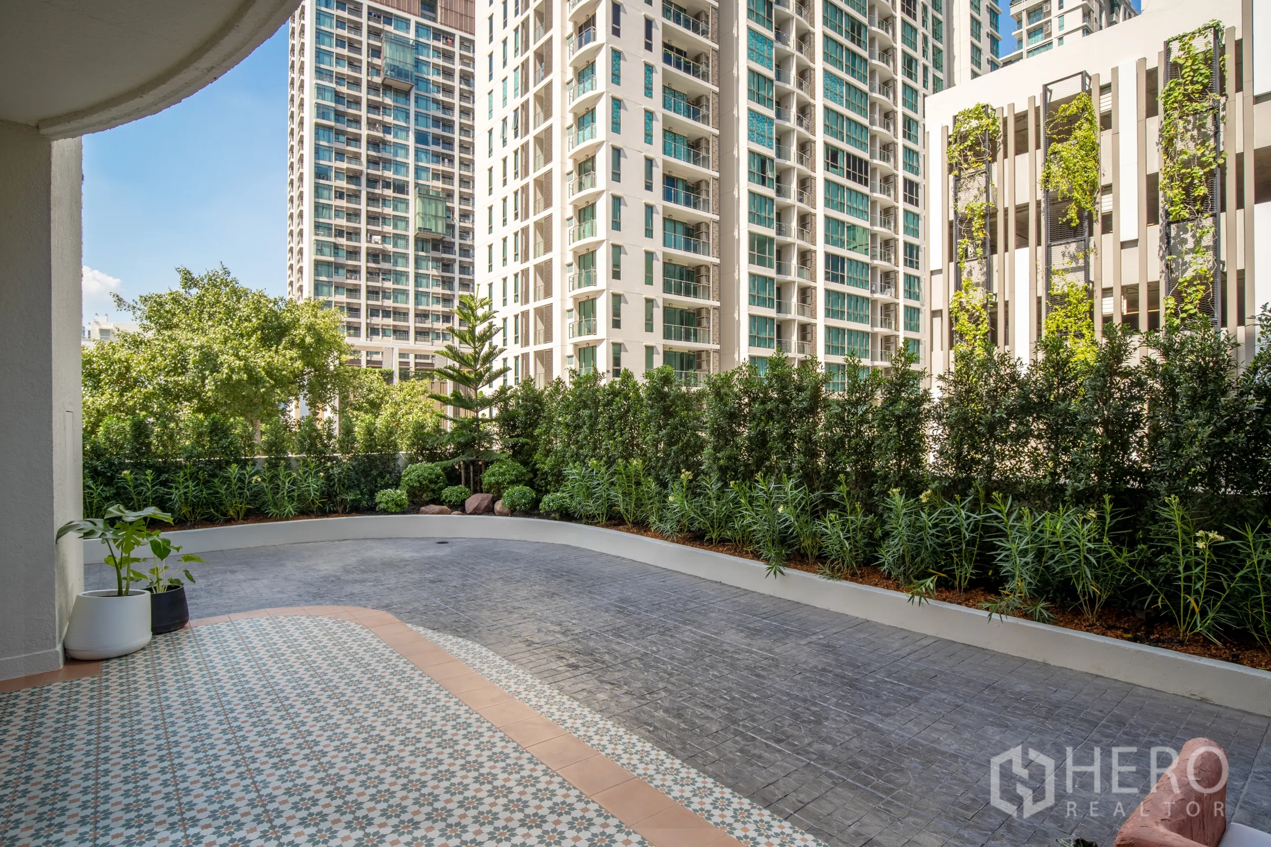 Condominium for sale in Watthana, Bangkok - Private ground terrace in Phrom Phong condo with hedge landscaping and high-rise views.