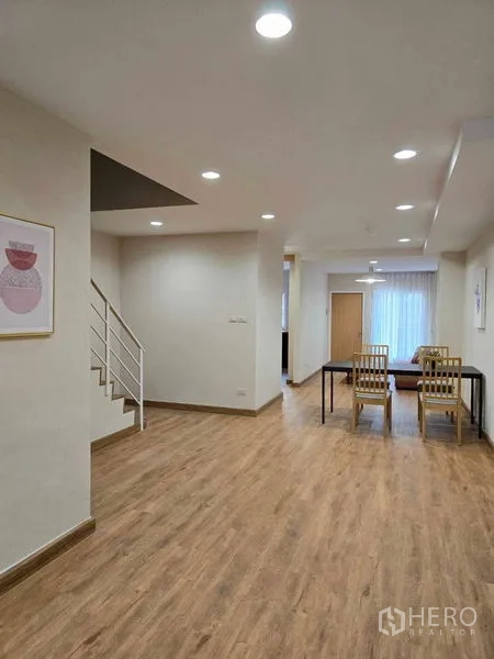 联排别墅 出租在Bang Na, Bangkok - 开放式客餐厅，楼梯与筒灯照明。