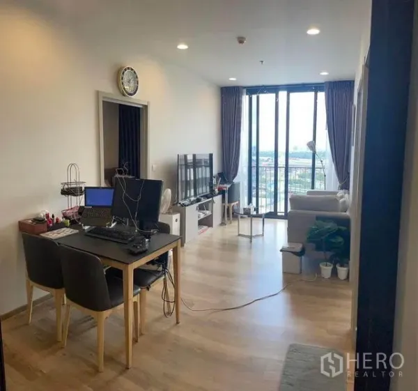 Condominium for rent in Khlong Toei, Bangkok - Living-dining area with TV console and large sliding doors opening to the balcony and city view.