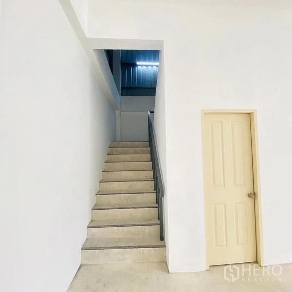 Warehouse for rent in Bang Khae, Bangkok - Stairwell and internal door within the warehouse, showing access to upper level and utility room.