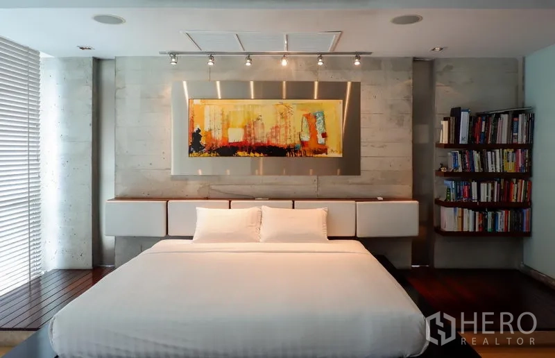 Condominium for rent or sale in Khlong Toei, Bangkok - King bedroom with wall art, track lighting and a curved bookshelf.