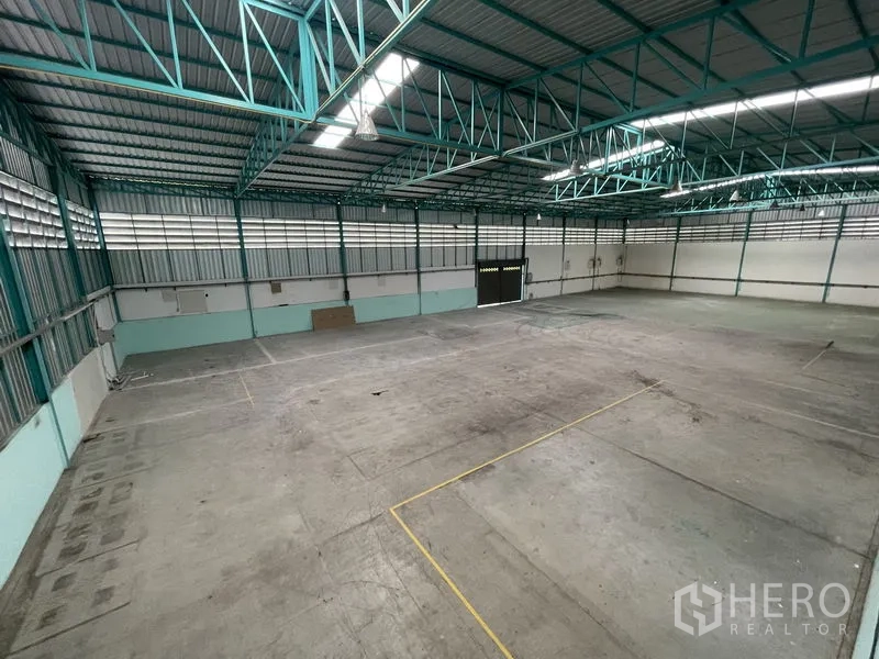 货栈 出租在Lat Lum Kaeo, Pathum Thani - 广角视角的空置仓库空间，钢梁结构、卷闸门与混凝土地面。