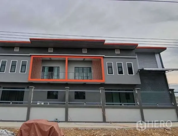 Warehouse for rent in Pathum Thani - Modern two-storey warehouse-office facade in Lam Luk Ka with orange balcony accents and a secure perimeter wall.