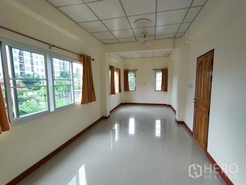 Detached House for rent in Khlong Toei, Bangkok - Sunlit upper room with large windows overlooking greenery and nearby buildings.