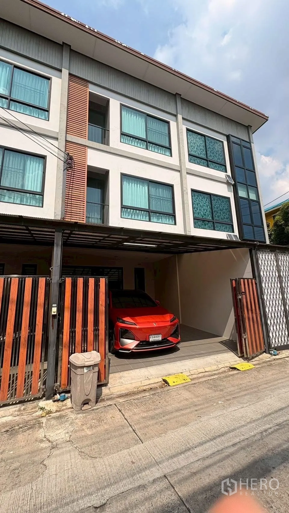 ทาวน์เฮาส์ for rent in Phra Khanong, Bangkok - ด้านหน้าทาวน์เฮ้าส์สามชั้นสมัยใหม่พร้อมที่จอดรถในร่มและประตูรั้ว